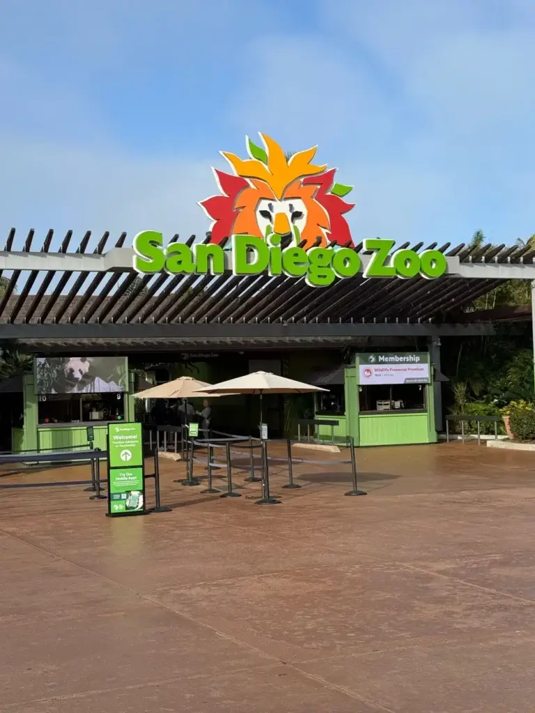 Entrance gate of the San Diego Zoo with a colorful lion logo and green signage.
