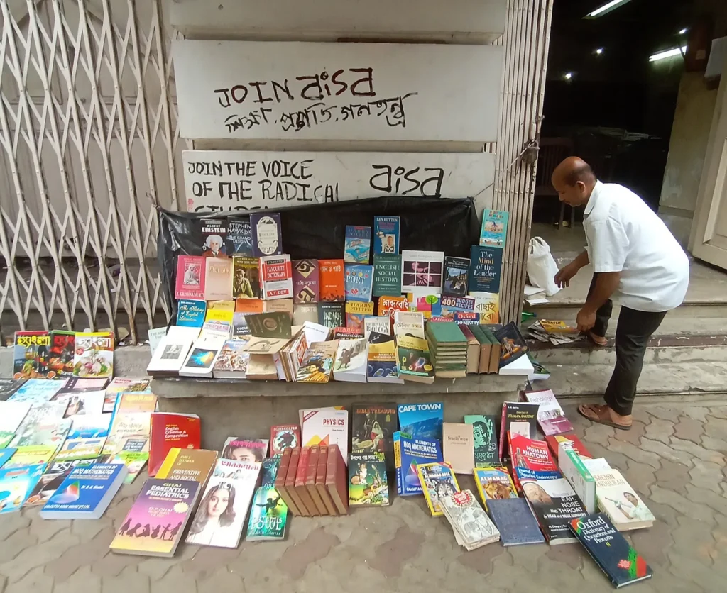 Bookseller with stacks of second-hand books at a College Street stall