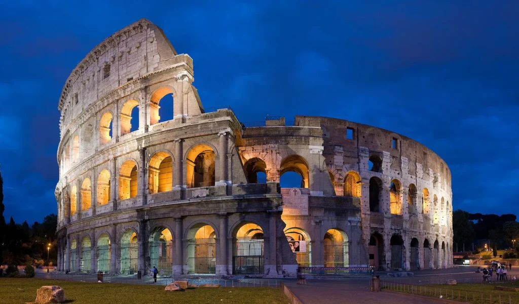 The Colosseum in Rome lit up against a deep blue evening sky