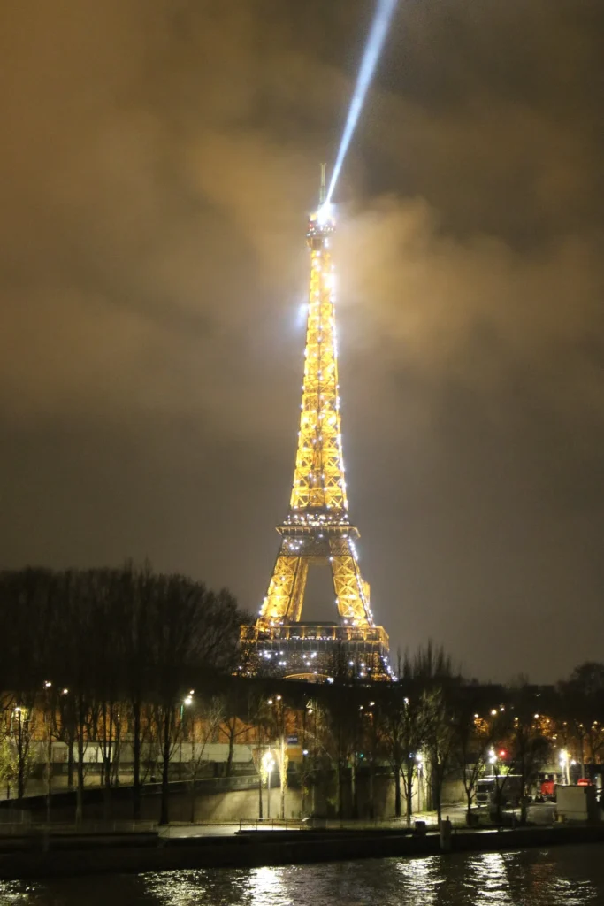 The Eiffel Tower lit in gold at night above the Seine
