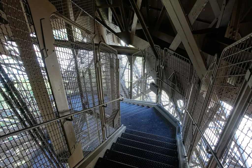 Metal stairs climbing through the iron lattice of an Eiffel Tower leg