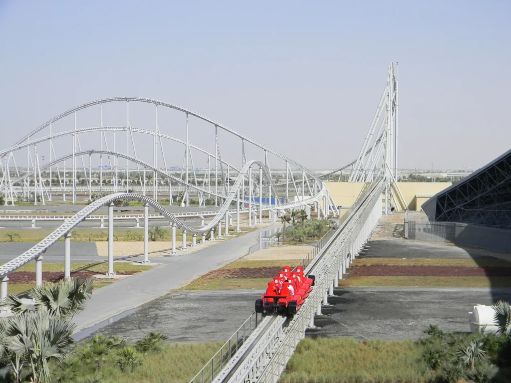 The Formula Rossa roller coaster track curving beside the red roof of Ferrari World Abu Dhabi