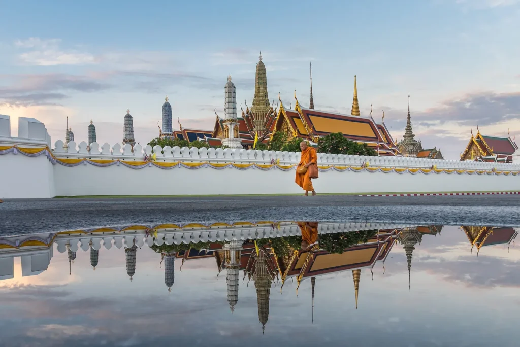 The golden spires of Wat Phra Kaew and the Grand Palace reflected in water in Bangkok
