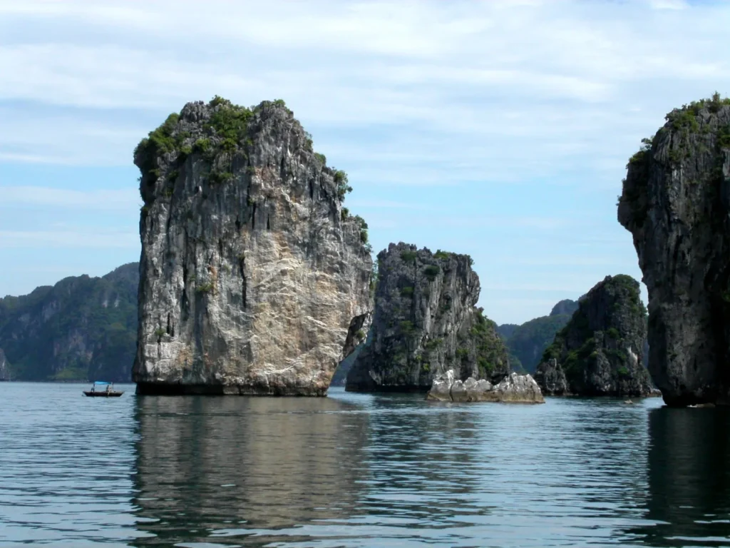 Tall limestone islets rising from calm green water in Ha Long Bay, Vietnam
