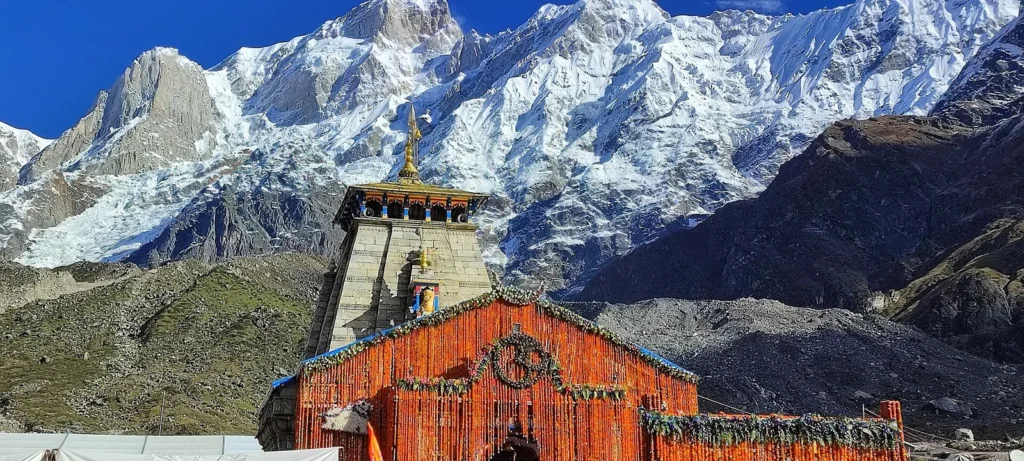 Stone Kedarnath shrine with mountains behind under a clear sky