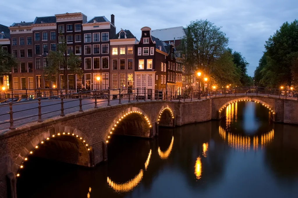 Arched bridges lit at night where the Keizersgracht meets the Reguliersgracht canal