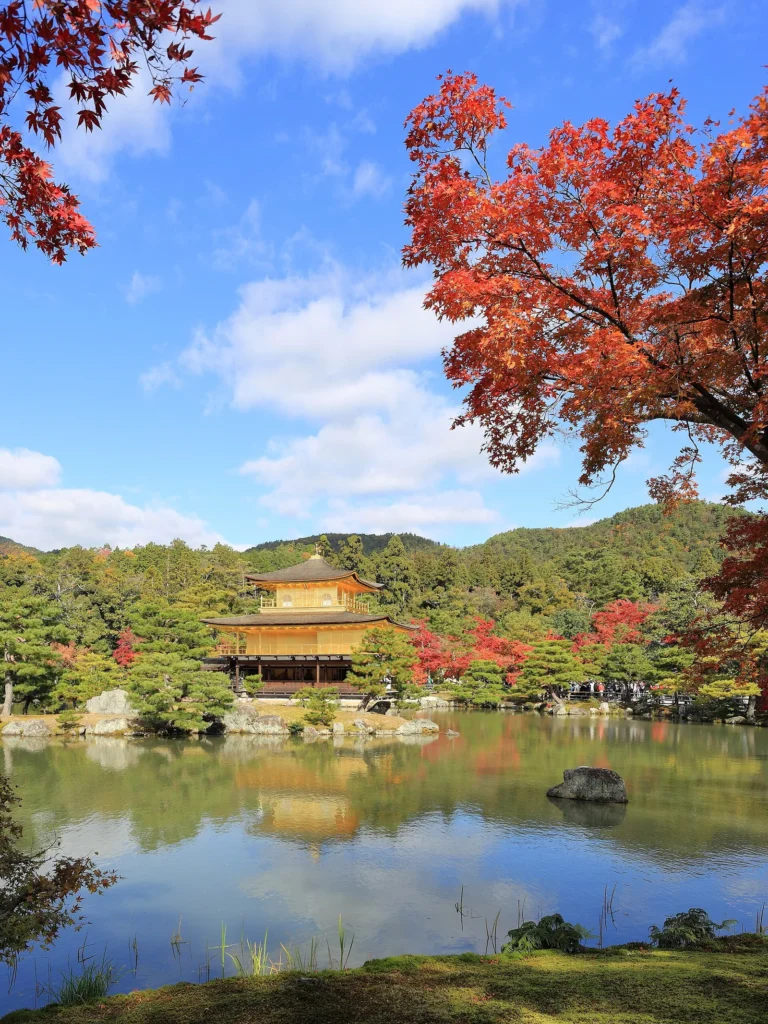 The gold-covered Kinkaku-ji pavilion beside a pond with autumn trees
