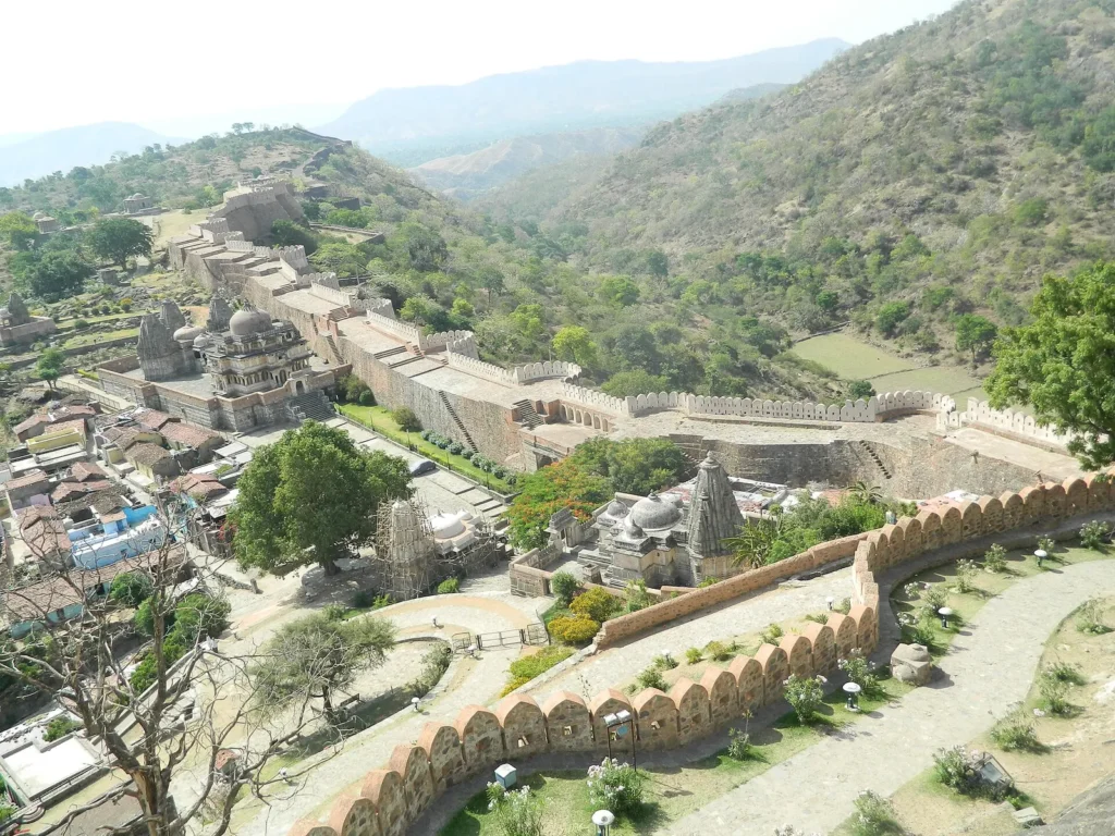 The long stone wall of Kumbhalgarh Fort winding over green Aravalli hills