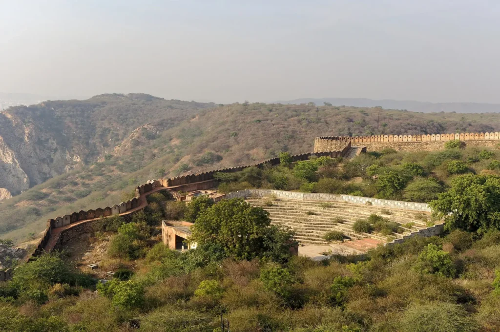 Open-air theatre area and fortification walls of Nahargarh Fort on a green hillside