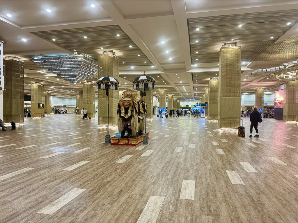 Wide hall with pillars and wooden-look floor inside the international terminal of Ngurah Rai airport in Bali