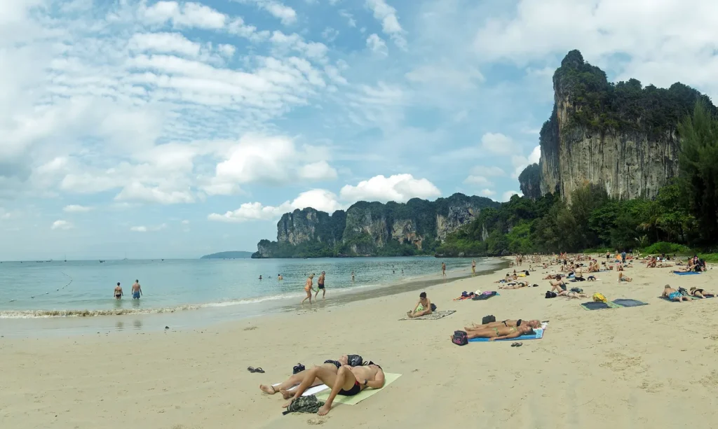 Railay Beach in Krabi with limestone cliffs behind the sand and longtail boats offshore