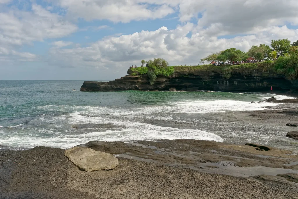 Waves breaking on dark rocks near the Tanah Lot sea temple on the coast of Bali