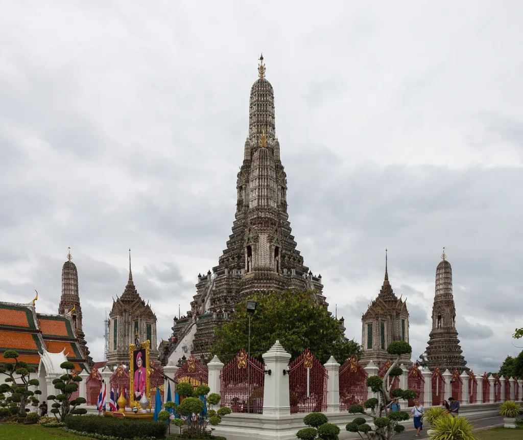 The tall central prang of Wat Arun in Bangkok against a cloudy sky
