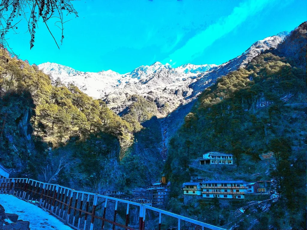 Yamunotri temple with an orange spire in a narrow valley below a glacier